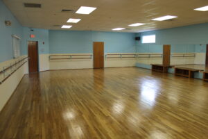 A large dance studio with blue walls and wood floors