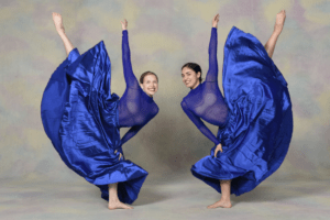 Two dancers doing leg extensions in large flowy skirts