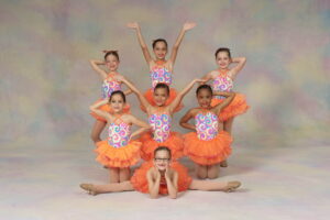 A group of young dancers pose in jazzy costumes