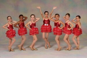 Young dancers pose in red costumes and tap shoes